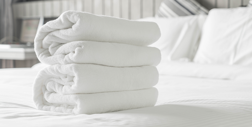 Folded clean towels and bed linens provided by professional Boca Raton cleaning services