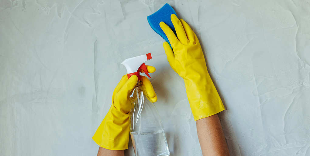 Gloved hands cleaning a wall, symbolizing the trained and detail-focused approach of Angelic Maids in Boca Raton.