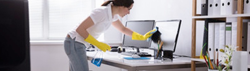 Woman cleaning home office monitor