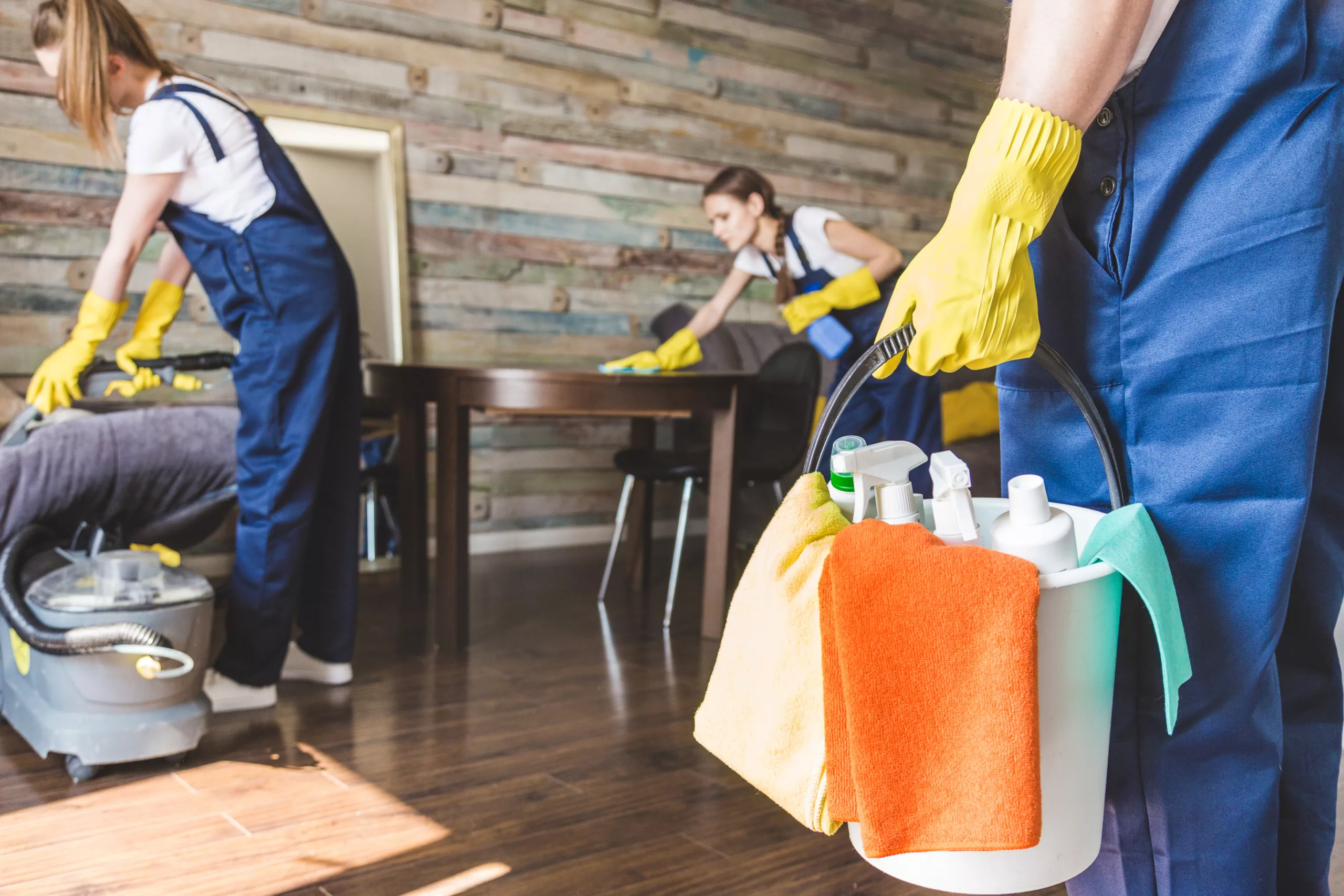 Cleaning service with professional equipment during work. professional kitchenette cleaning, sofa dry cleaning, window and floor washing. man and women in uniform, overalls and rubber gloves.