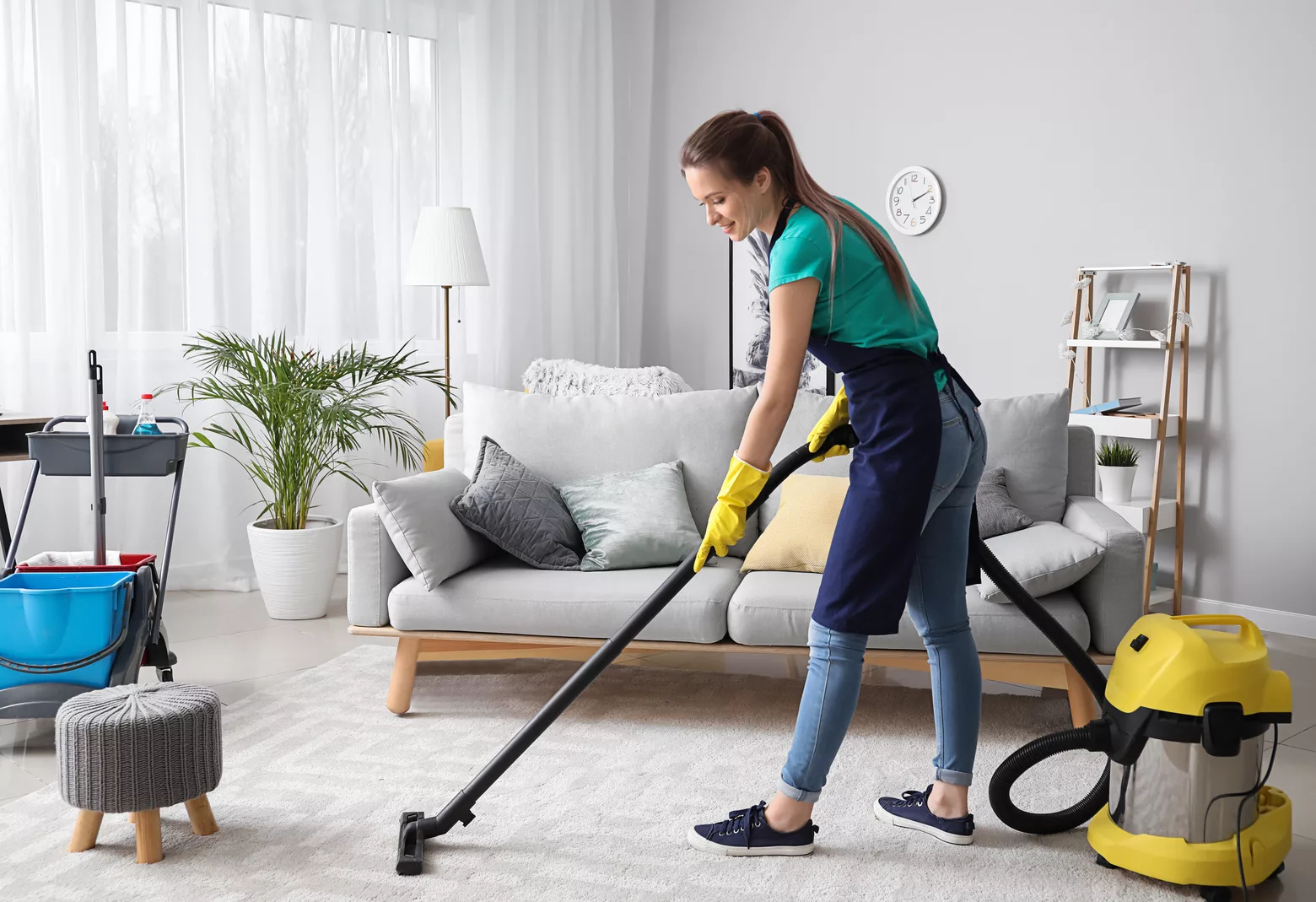 Female cleaning expert with vacuum cleaner in room