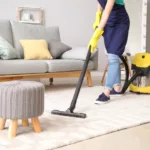 Female residential cleaning service expert with vacuum cleaner in room